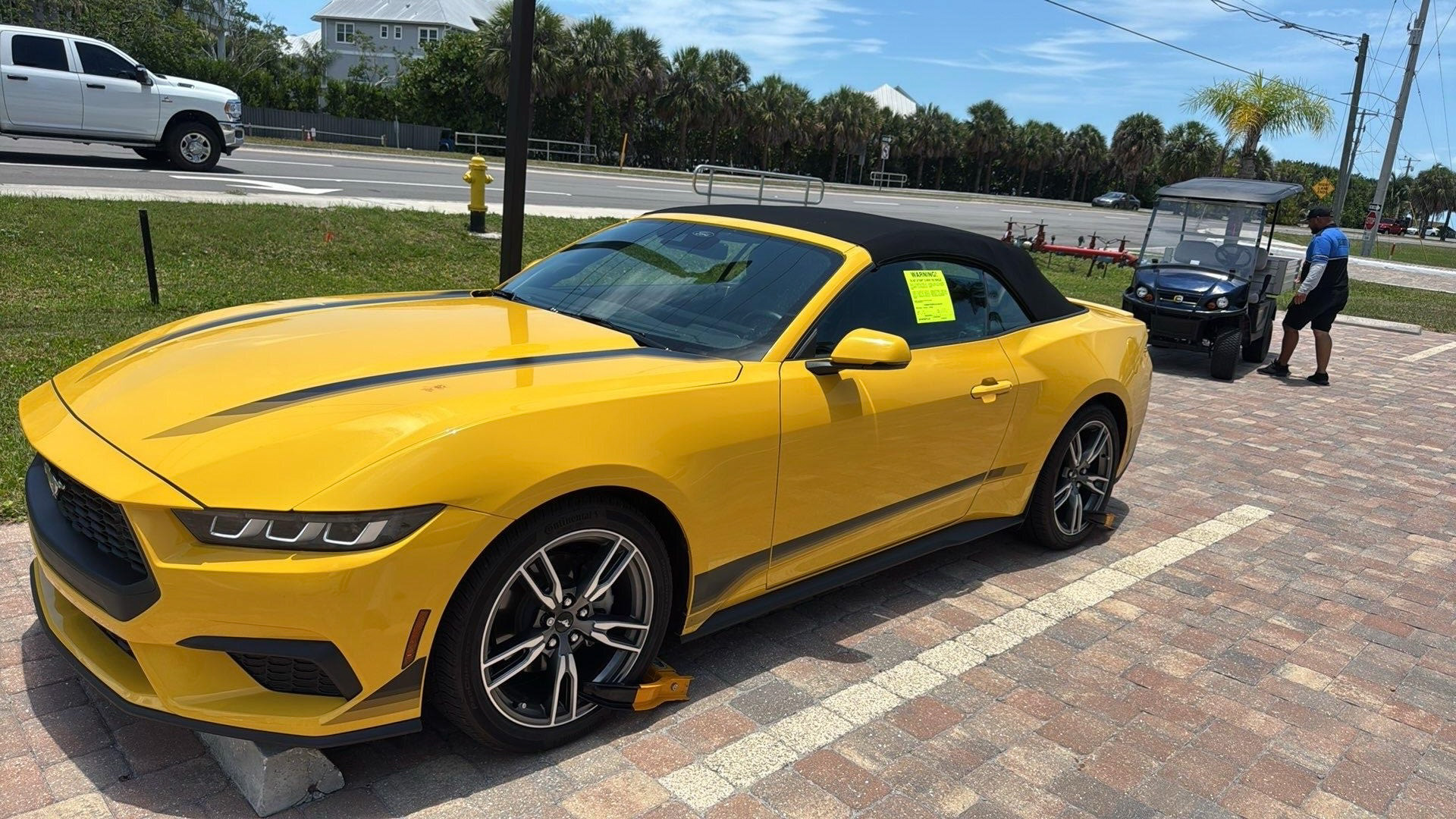 Yellow vehicle immobilized with wheel lock and warning notice